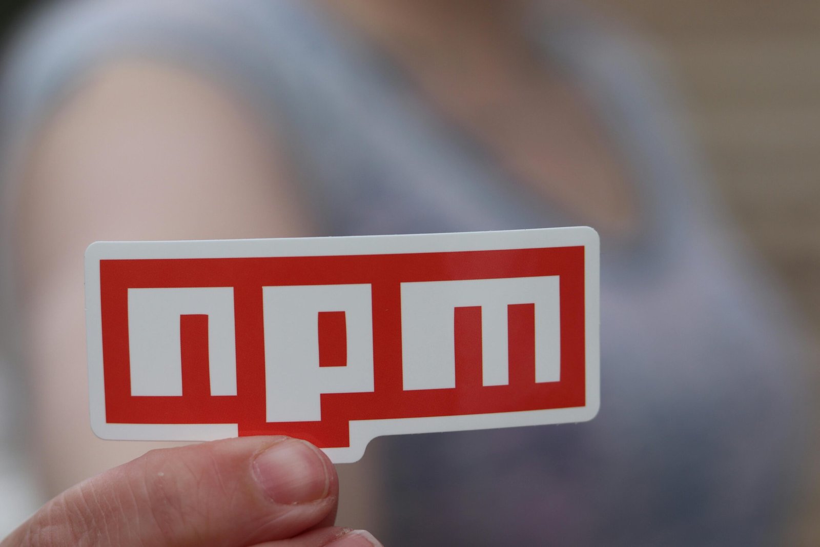 Person Holding a Red NPM Sticker